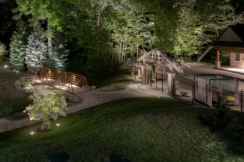 a large backyard at night well lit using landscape lighting